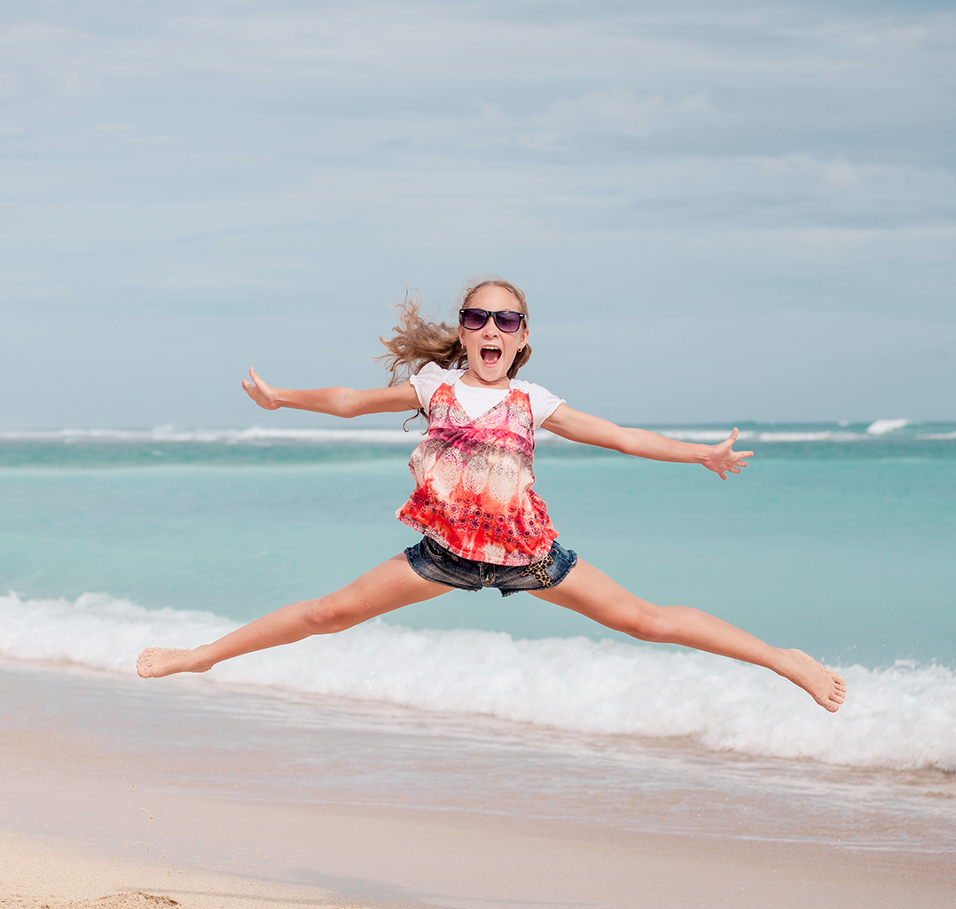 Happy teen girl  jumping on the beach at the day time